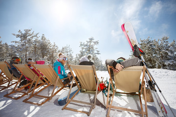 Wall Mural - Friends on skiing sunbathing in sunbed on ski terrain, back view