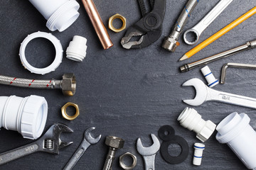 Plumbing concept. tools and pipes on a dark slate bakground