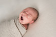 © Alison Winterroth Photography/Stocksy - Newborn baby boy yawning while lying on the bed
