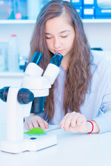 Poster - schoolgirl in a class of biology is studying a green plant