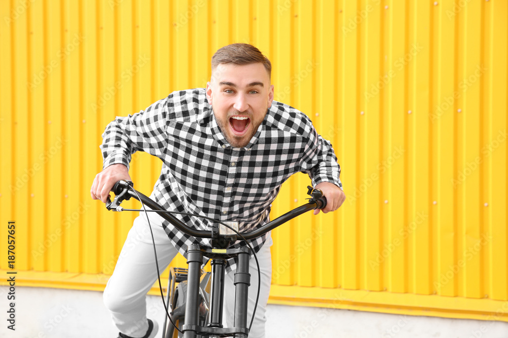 Handsome young hipster man with bicycle near wall outdoors