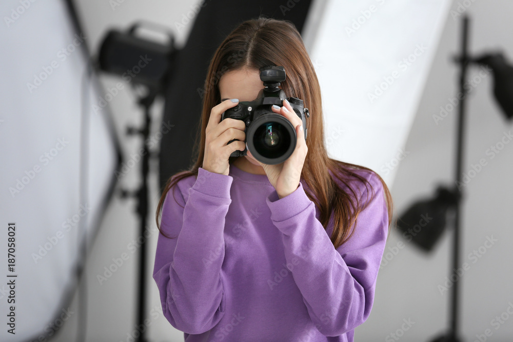 Beautiful young photographer taking photo in professional studio