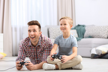 Canvas Print - Cute little boy with father playing videogame at home