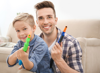 Poster - Cute boy and his father playing with toy guns at home