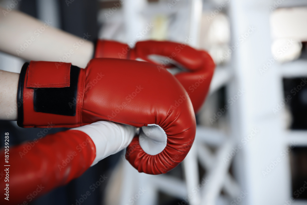 Boxer holding hands in gloves on rope of boxing ring