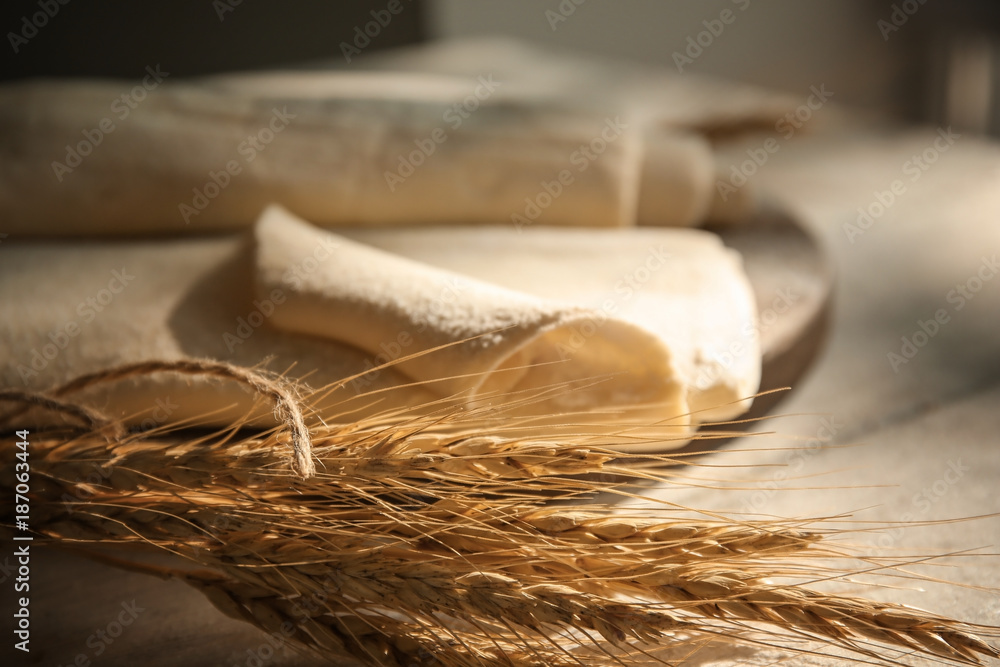 Wheat heads and fresh raw puff dough on table