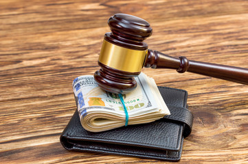 Judges hammer with folded dollars and wallet on the table.