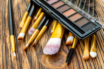 Makeup brushes with eyeshadow on wooden table. Close up.