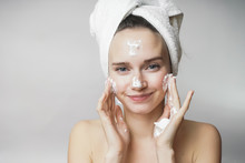 Funny Woman In A Towel On The Head Happy Cleanses The Skin With Foam On A White Background Isolated. Skincare Cleansing Concept