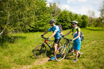 Wall Mural - ACTIVE Young couple biking on a forest road in mountain on a spring day