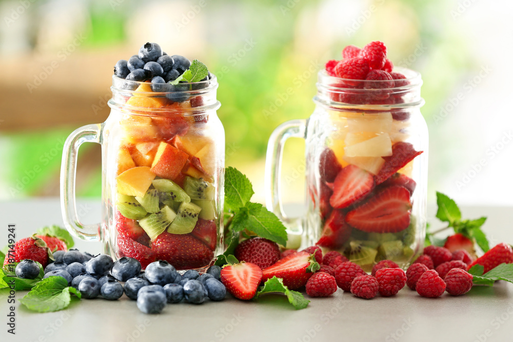 Mason jars with fruits and berries on table