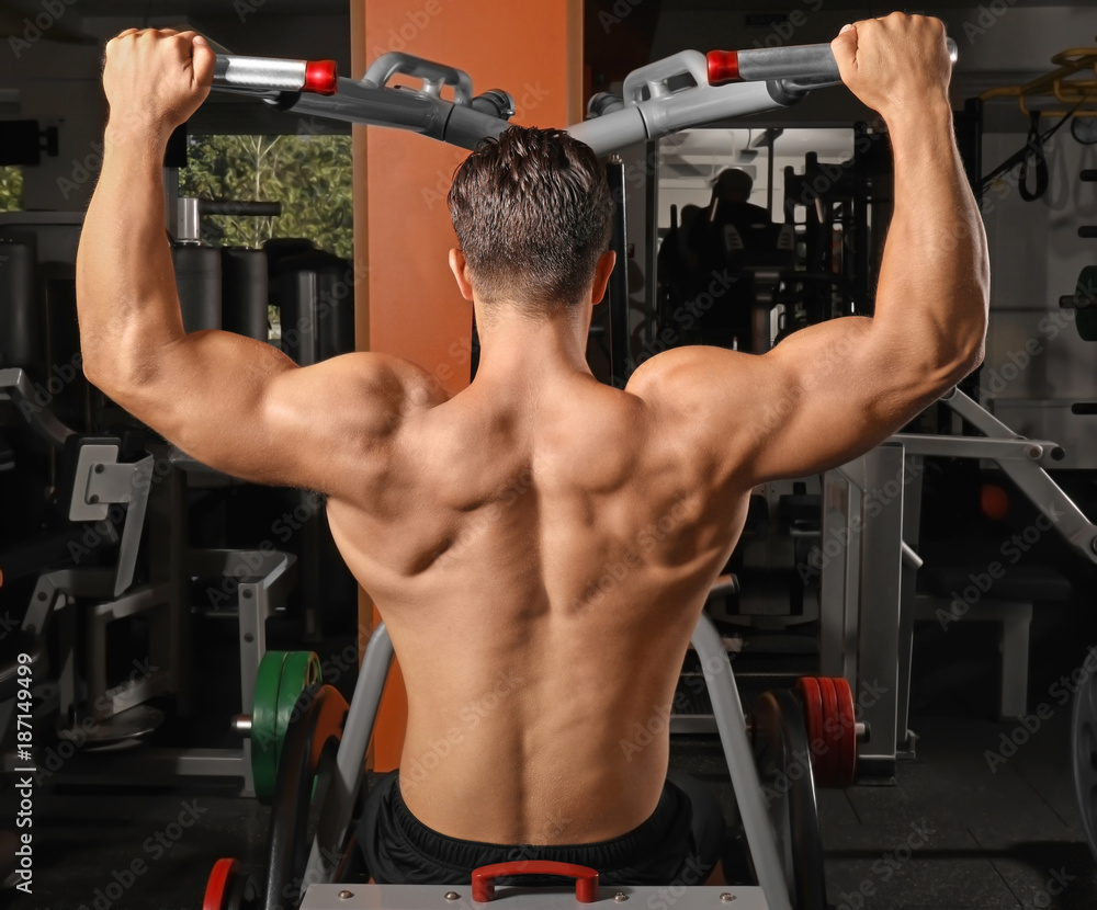 Young man training on exercise machine in gym