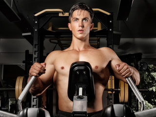 Young man training on exercise machine in gym