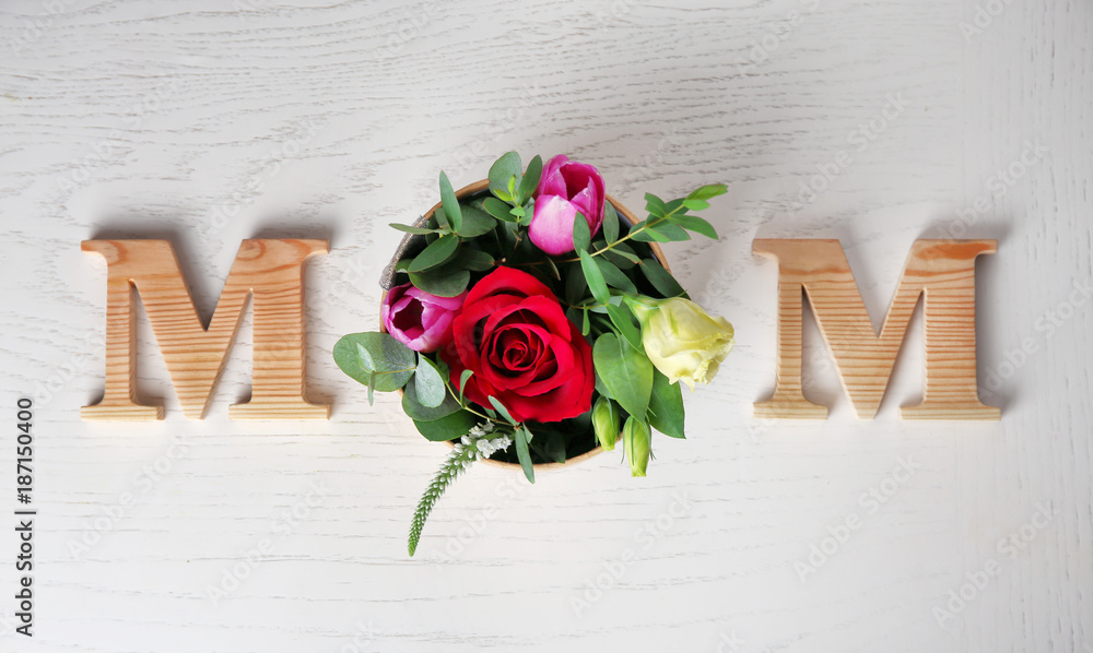 Word "Mom" and fresh flowers on light background. Mother's Day composition