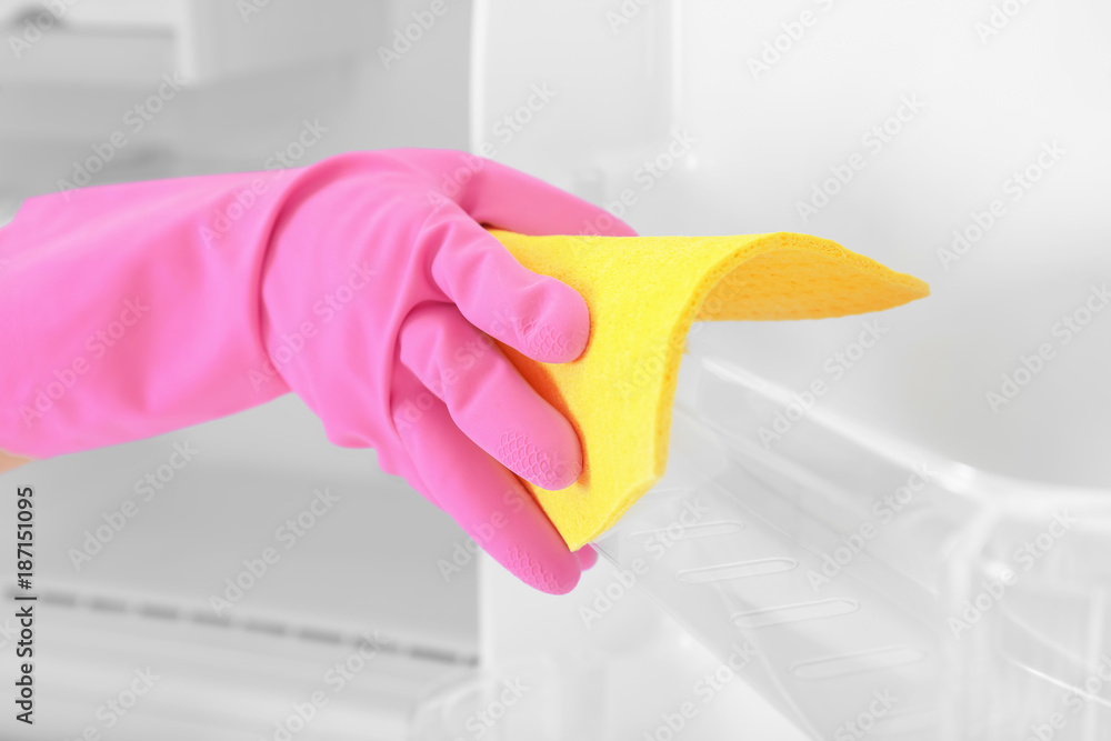 Person washing refrigerator with rag, closeup