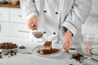 © Africa Studio - Female chef decorating tasty chocolate cake in kitchen