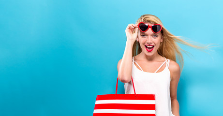 Young woman holding a shopping bag on a solid background