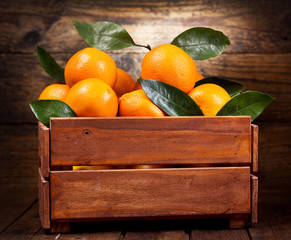 Wall Mural - fresh orange fruits with leaves in a wooden box