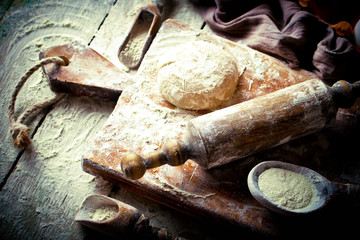 Wall Mural - Dough with flour on an old background in a composition with kitchen accessories