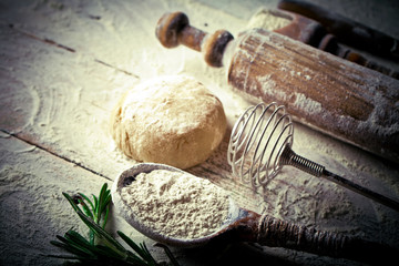 Wall Mural - Dough with flour on an old background in a composition with kitchen accessories