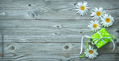 Fotografie, Obraz Gift box and daisy flowers on old wooden planks