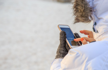 woman writing message on the phone in the street in winter