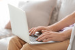 © Africa Studio - Young man using his laptop while sitting on sofa indoors
