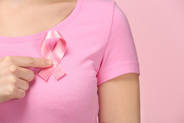 Sticker - Woman showing pink ribbon on color background. Breast cancer awareness concept