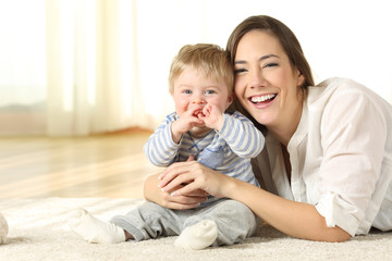 Wall Mural - Smiley mother and baby looking at you at home