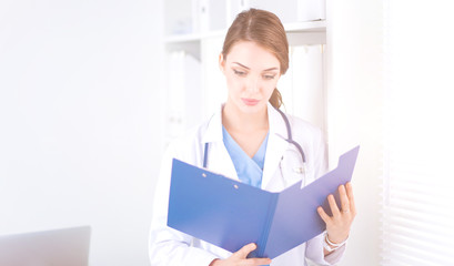 Wall Mural - Smiling female doctor with a folder in uniform standing at hospital