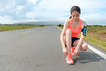 Wall Mural - smiling attractive runner tying shoelace on road