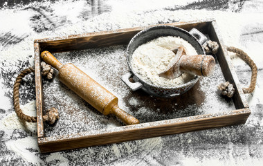 Flour in a bowl with rolling pin in a wooden box.