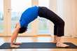 Man practicing yoga indoors in a retreat space doing Full Wheel Pose - Urdhva Dhanurasana