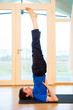 Man practicing yoga indoors in a retreat space doing Supported Shoulderstand Pose - Salamba Sarvangasana