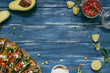 Mexican tacos with salsa and avocado on the wooden blue background, top view