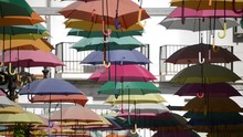 Heap Of Colors Umbrellas Hanging In A Village Square A Sunny Day