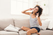 © Prostock-studio - Happy young woman in headphones on beige couch