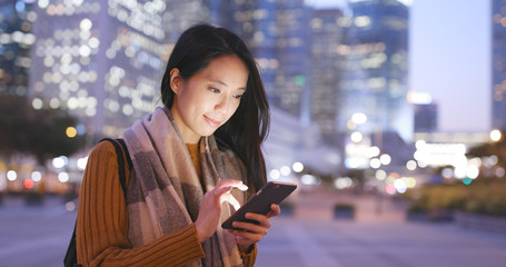 Woman looking at smart phone in the city at night