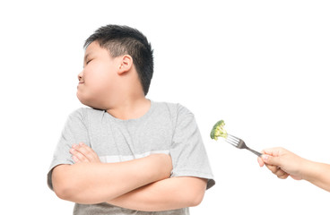 obese fat boy with expression of disgust against vegetables