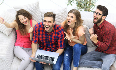 Wall Mural - group of friends watching a video on a laptop and laughing