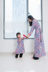 Wall Mural - Vietnamese mother and daughter in Ao Dai Traditional dress, celebrate new year at home. Tet Holiday.