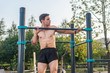 © undrey - Young male athlete doing chin-up exercises in the park. Fitness man working out outside