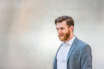 Portrait of Young American Hipster Businessman with full beard on silver metal background..