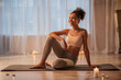 © Yakobchuk Olena - Portrait of excited young woman relaxing after training. She is sitting on carpet and smiling. Candles are on floor