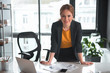 © Yakobchuk Olena - Portrait of smiling female standing near modern desk. Laptop, mobile and different documents locating on it. Labor concept