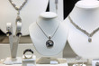 Srebrny naszyjnik, kolczyki i pierścień z diamentami na białych popiersiach w sklepie jubilerskim.