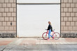 © Guille Faingold/Stocksy - Woman walking with bicycle along the street.
