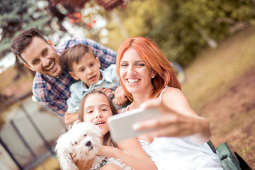 Wall Mural - Smiling young family taking selfie in the park.