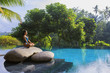 © Felix Hug/Stocksy - Yoga by a tropical pool setting.
