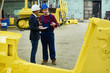 © Seventyfour - Full length portrait of handsome industrial engineer wearing overall and hardhat showing production department of modern heavy equipment factory to inspector while he taking necessary notes.